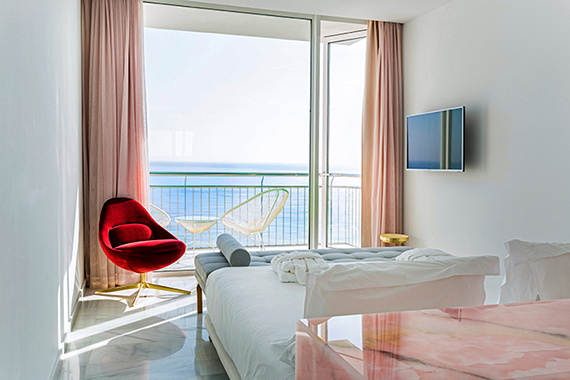 Fotografia d’interior. Una habitació amb balcó i vistes al mar.